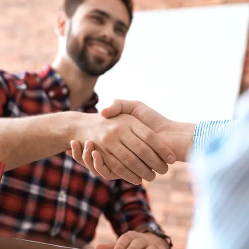 Two men shaking hands over approved financing terms.